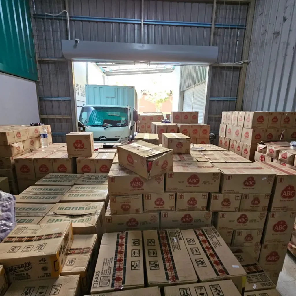 Industrial warehouse showing ABC brand inventory with truck loading operations distributed by Sinarmas Marketing