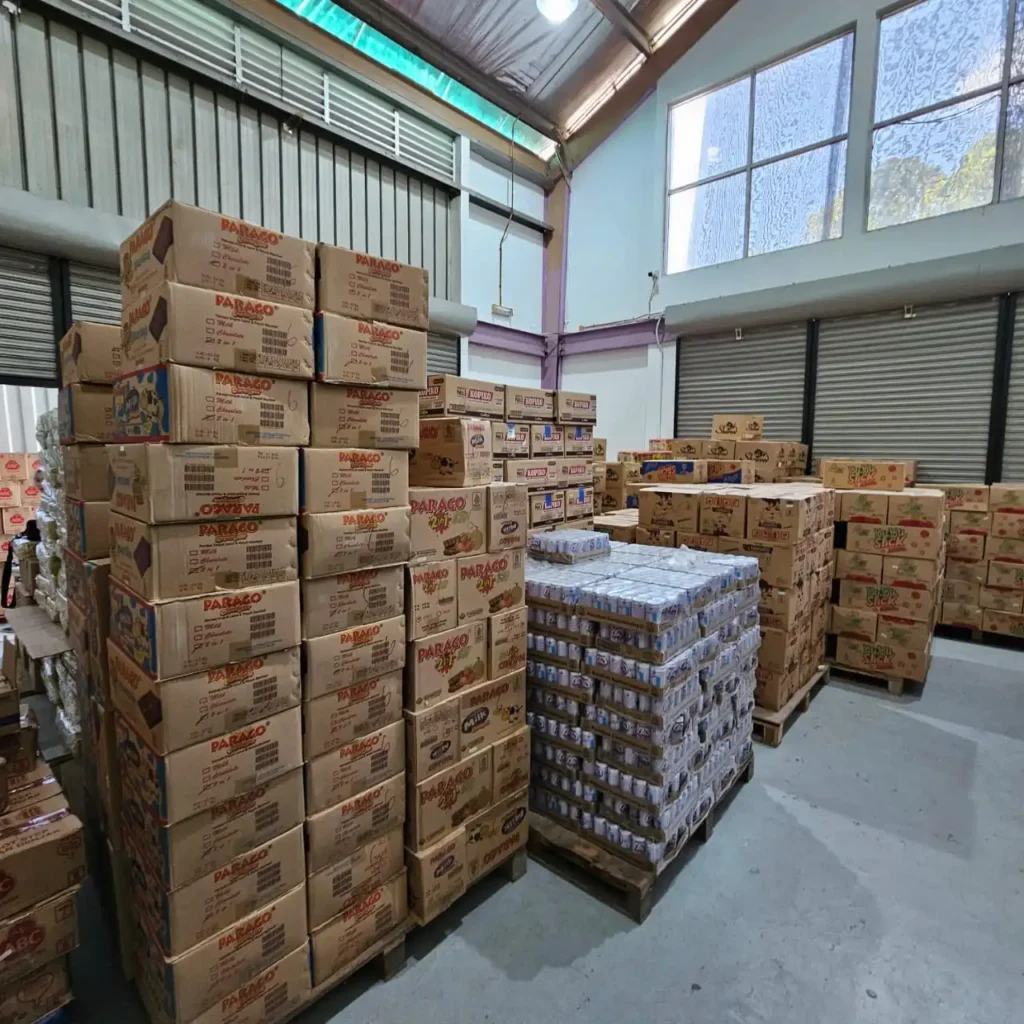 Industrial storage facility with organized product stacks including Parago brand items and beverages from Sinarmas Marketing